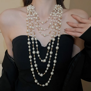 Close-up of a multi-layer white pearl necklace with gold beads on a black garment