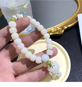 Detail of white Bodhi seed bracelet with flower pendant and green bead accents