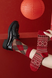 Détail du tricot de chaussettes en laine épaisses rouges avec motifs Fair Isle et losanges