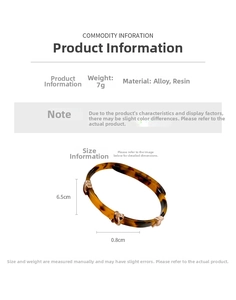 Detailed view of leopard print resin open bracelet with three gold knot accents