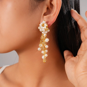 Detail of floral drop earrings with pearls and crystals worn on ear for elegant style