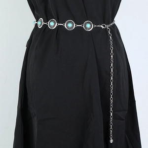 Detail of silver chain belt with blue stone accents worn on a black dress waist