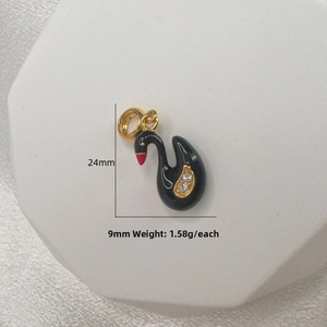 Detailed macro view of a black enamel swan pendant with gold plating and crystal accents