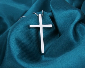 Vue macro d'un pendentif croix en argent sterling S925 poli avec sa chaîne à billes