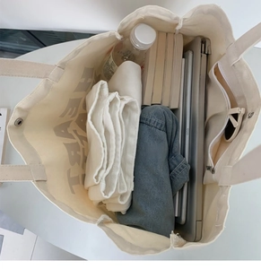 Large white canvas tote bag with snap button and interior pocket showing high capacity