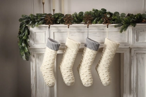 Detail of knitted Christmas stockings with fish scale texture hanging on a fireplace