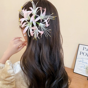Detail of red Lycoris flower hair clip on wavy hair for elegant New Year styling