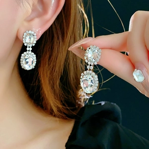 Detail of silver drop earrings with rectangular clear crystals and diamond pavé accents