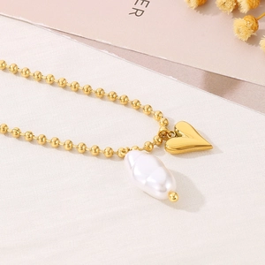 Detail of golden ball chain necklace featuring a 3D heart pendant and baroque pearl