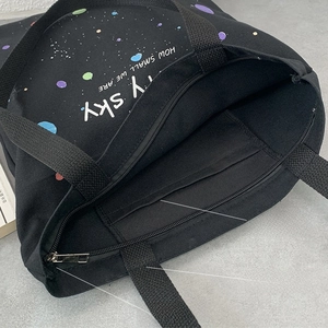 Détail du sac en toile noire montrant la fermeture éclair et la poche intérieure portable