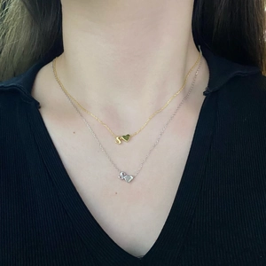 Close-up of S925 silver necklaces with letter S and heart pendants in gold and silver