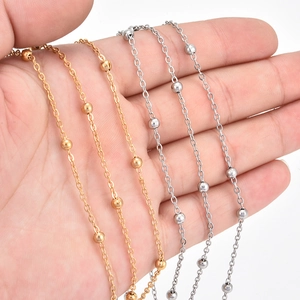 Polished gold and silver stainless steel beaded cross chains held in hand for DIY jewelry
