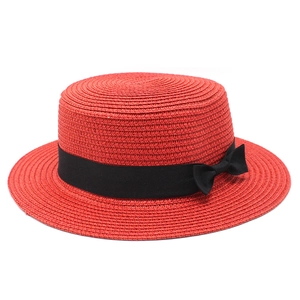 Detailed texture of red straw boater hat with a black grosgrain ribbon and bow detail
