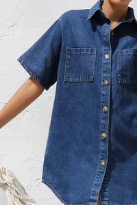 Detail of dark blue denim shirt dress featuring button-down front and dual chest pockets