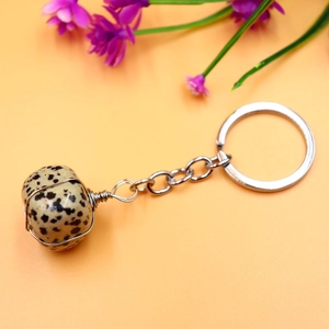 Macro view of a wire-wrapped natural stone keychain with copper wire on a soft orange background