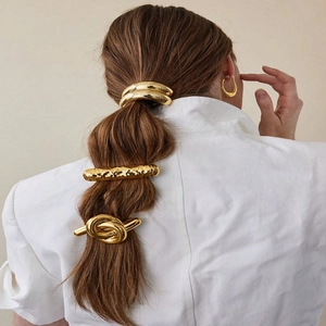 Detail of golden lava textured hairpins and circular clip on model with white shirt