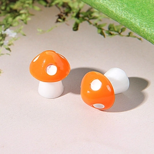 Close-up of two miniature orange resin mushrooms with white dots for micro landscapes