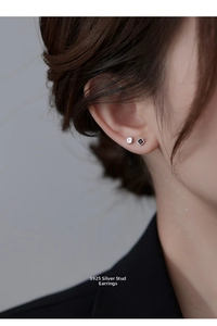 Macro shot of S925 silver square stud earrings with black and clear stones on ear