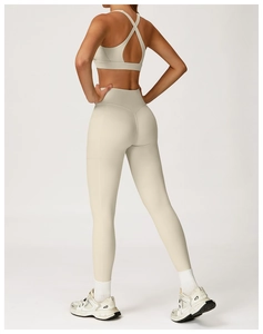 Detail of high-waist beige yoga leggings with side pockets and cross-back sports bra