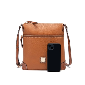 Brown pebble leather crossbody bag detail with multiple zippers and phone for scale