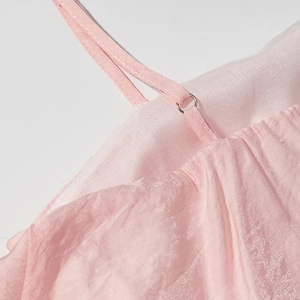 Détail de la robe rose à volants montrant les fines bretelles et boucles métalliques