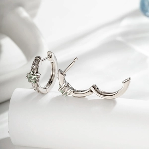 Créoles en argent avec zircon étoile vert menthe et pierres claires sur tissu blanc