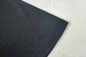Détail de la double couture sur l'ourlet d'une robe moulante en tricot noir