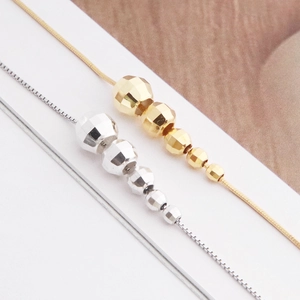 Detailed view of silver and gold faceted bead necklaces with shiny metal finish