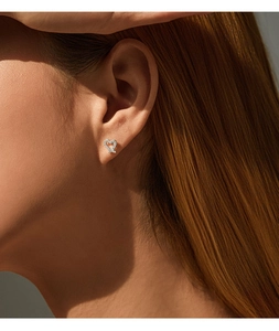 Close-up of heart-shaped silver stud earring with sparkling clear stones on a model