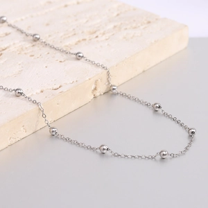 Minimalist silver stainless steel beaded cable chain necklace on a stone background