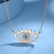 Macro detail of rose gold evil eye pendant with blue crystals and sparkling micro pave