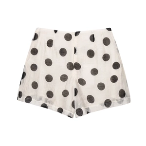 Detail of high-waist white polka dot shorts with textured fabric and hidden back zipper