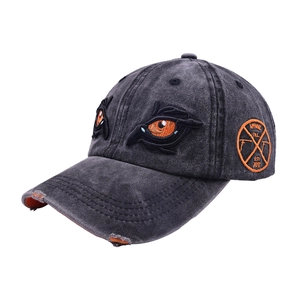 Detailed close-up of 3D monster eyes embroidery and distressed brim on gray baseball cap