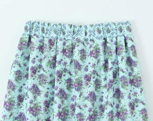 Detail of light blue floral skirt featuring purple print and elastic waist stitching