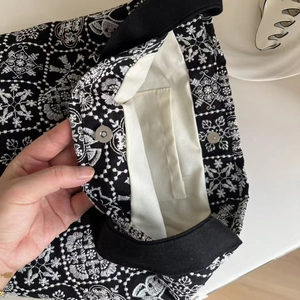 Detail of floral embroidery on black canvas bag with magnetic buckle and interior pocket