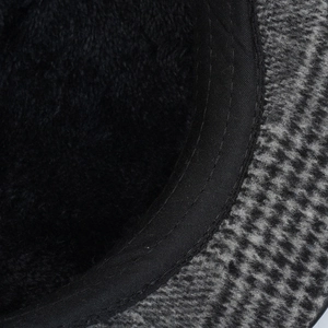 Detail of warm black fleece lining and grey houndstooth wool fabric on a winter cap