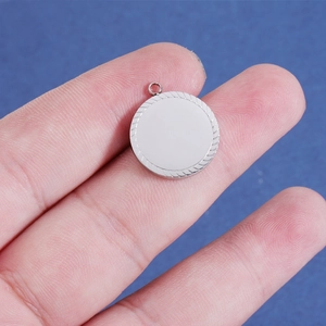 Detail of a silver mirror-polished circular pendant with a decorative twisted border edge