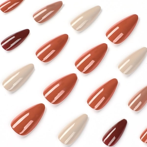 Glossy almond press-on nails in caramel and earthy tones set on a white background