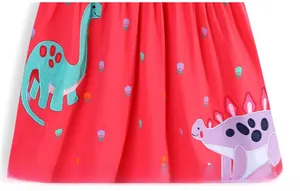 Dettaglio di un abito rosso da bambina con ricamo a dinosauro e piccoli fiori colorati