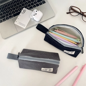 Polka dot felt pencil cases in navy and grey with stationery on a modern desk