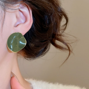 Close-up of model wearing dark green geometric enamel earring with 14k gold plating