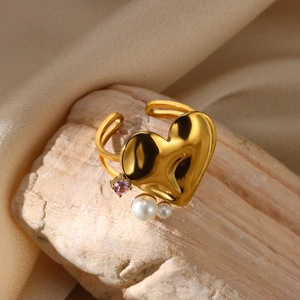 Detailed macro view of heart shaped gold ring featuring white pearls and pink gemstone