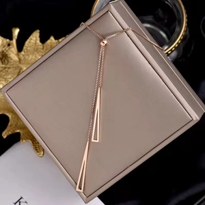 Detail of rose gold double chain necklace with hollow triangle pendants on jewelry box