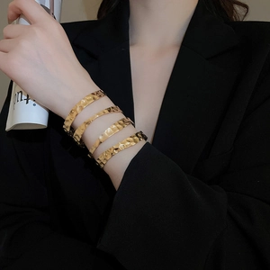Macro detail of the irregular hammered texture on gold-plated layered metal bangles