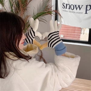 Close-up of striped knitted gloves with multi-color patchwork and ribbed cuffs on hands