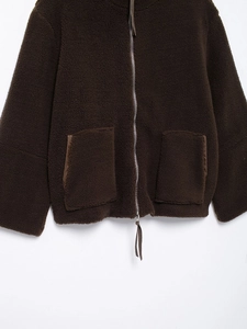 Detail of dark brown teddy fleece jacket featuring zip closure and front patch pockets