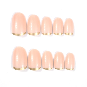 Detail of short oval press-on nails featuring nude base and elegant golden French tips