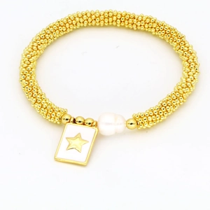 Detail of bohemian gold beaded bracelet with white pearl and star engraved square pendant