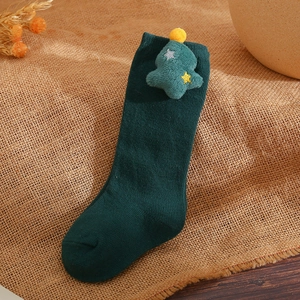 Close-up of dark green children's high sock with plush Christmas tree and star detail