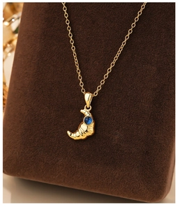 Macro detail of a gold croissant pendant necklace with a blue gemstone inlay on velvet